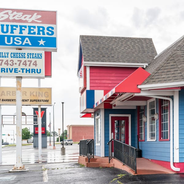 Steak Stuffers USA restaurant with a large sign advertising Philly Cheese Steaks and drive-thru.