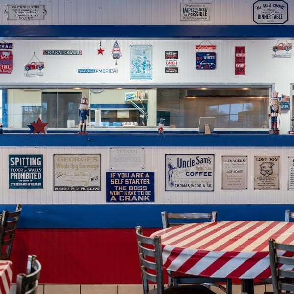 Restaurant interior with red and white striped tablecloths, blue and white walls, and patriotic decor.