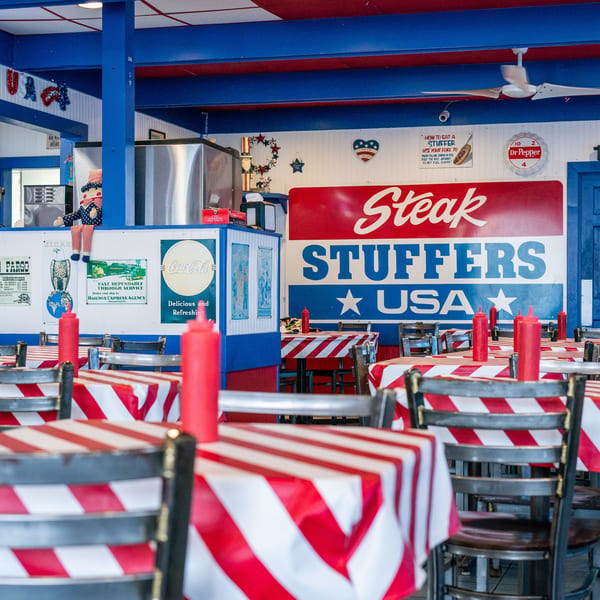Interior of Steak Stuffers USA, featuring red and white striped tables, blue walls, and patriotic decor.